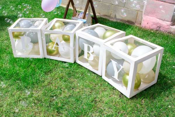 Baby spelled out on creative boxes filled with balloons at a gender reveal party.