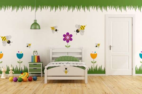 A child's bedroom with colorful garden-themed decals on the wall. There is a twin bed, a nightstand, and toys on the floor.