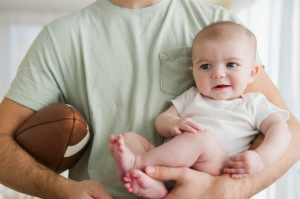 Father holding football and baby