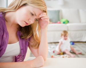 Mother with head in hands, baby in background