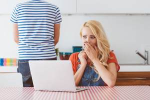 Worried woman using a laptop in the kitchen