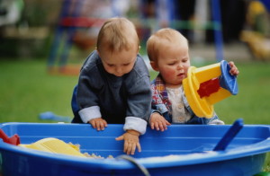 Two toddlers playing in sandpit, outdoors