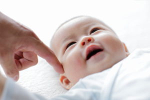 Smiling baby with finger of father,close up