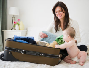 USA, New Jersey, Jersey City, Mother with baby daughter (6-11 months) packing suitcase