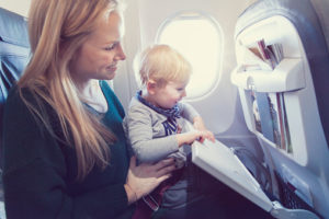 Mother w25 and son m2 sitting in an airplane, him stowing away the tray table