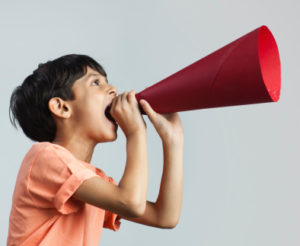Boy (6-7) shouting through paper megaphone