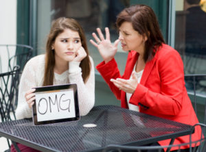 Caucasian girl with tablet as mother chastises her at cafe