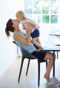 Mid adult woman holding up and kissing toddler daughter