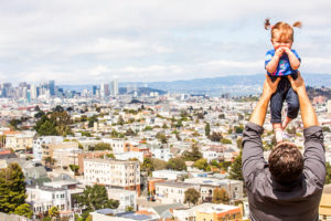Caucasian father lifting daughter over San Francisco cityscape, California, United States