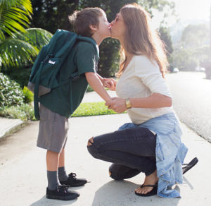 Boy kissing mother goodbye walking to school