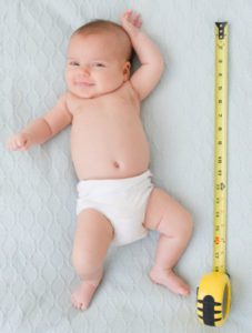 USA, New Jersey, Jersey City, baby girl laying (2-5 months) laying next to measuring tape
