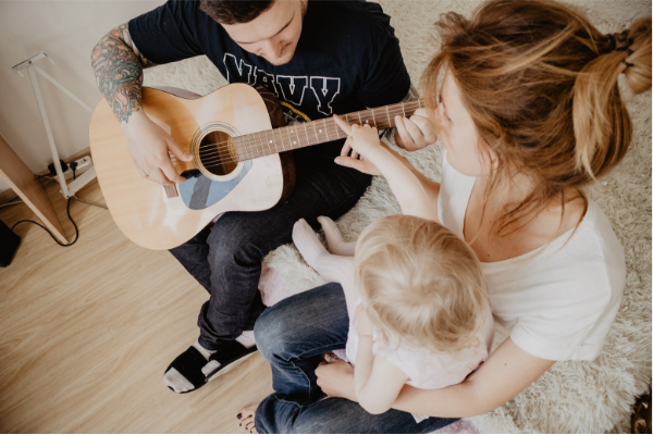 father playing guitar while mother and child sing along