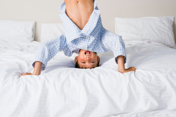 boy standing on head on a bed representing not going to sleep at night