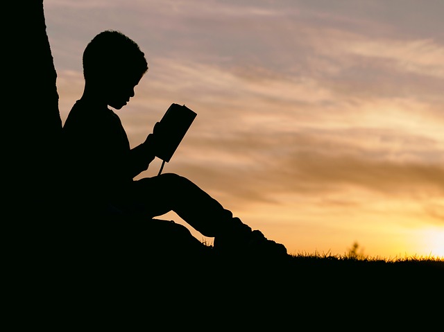silhouette of a little boy learning to read