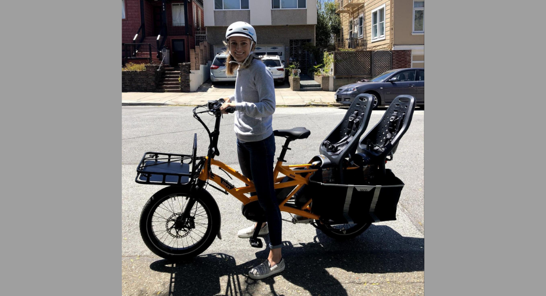 san francisco mom posing with electric cargo bike that fits two toddlers