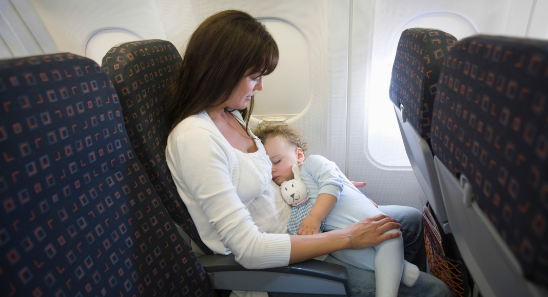 Mother holding sleeping baby on airplane