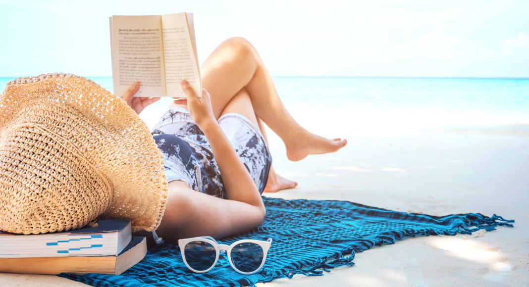 woman lounging at beach reading a book