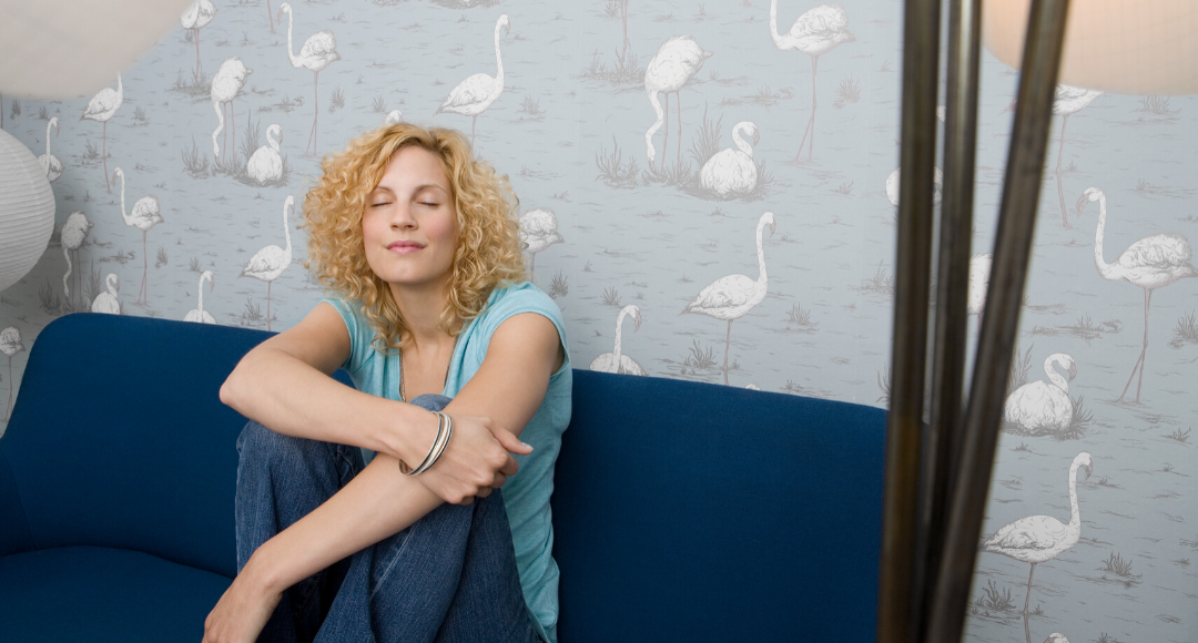 Calm and relaxed woman meditating on couch