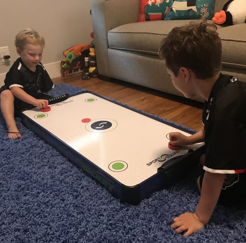 two boys playing with their small air hockey table