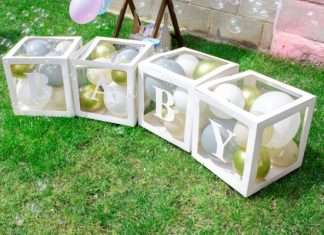 Baby spelled out on creative boxes filled with balloons at a gender reveal party.