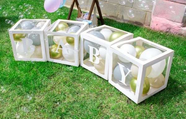 Baby spelled out on creative boxes filled with balloons at a gender reveal party.