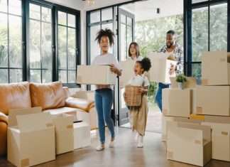 What To Consider When Moving to California With Your Family A family of two adults and two children is walking into a home with large windows and stacks of moving boxes.