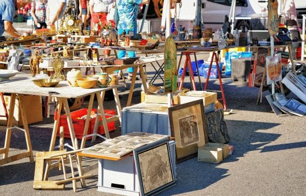 Easy DIY Decor Inspired by Bay Area Flea Markets Shoppers browse tables filled with vintage antiques, framed artwork, and collectibles at an outdoor flea market.